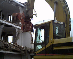 Excavadora CAT de excavaciones Félix López realizando demolición de vivienda en Salamanca. Esta demostración de maquinaria avanzada y experiencia en demolición y retirada de escombros resalta la versatilidad de excavaciones Félix López en todo tipo de servicios de obra civil.